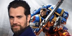 Henry Cavill in posa accando ad una scena del capitano Titus, protagonista di Warhammer 40k Space Marine. Il super soldato del videogioco è armato di spada dentata, simile ad una motosegna e indossa la tipica armatura super corazzata degli space marine ed è in corsa con la luce che lo illumina. L'attore davanti mostra un sorriso da posa e cattura lo schermo con lo sguardo.